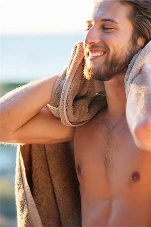 Happy man wiping himself with a towel on the beach Stock Photo - Premium Royalty-Free, Code: 6108-06905393