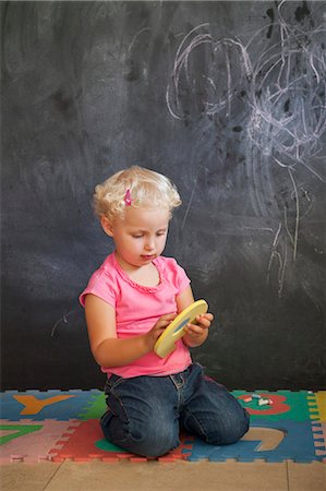 Girl playing with number puzzle in front of a black board Stock Photo - Premium Royalty-Free, Code: 6108-06905313