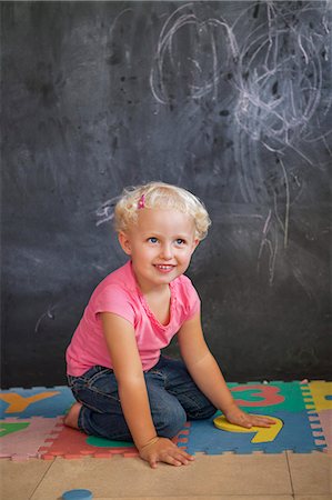 playing on the floor - Girl playing with number puzzle in front of a black board Stock Photo - Premium Royalty-Free, Code: 6108-06905323