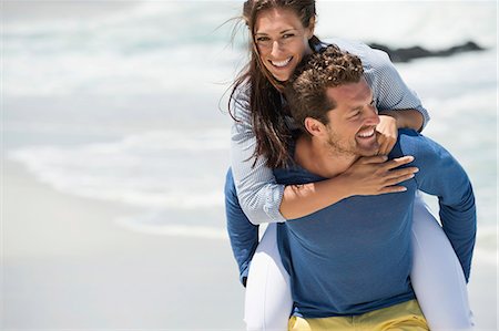 Man giving piggyback ride to his wife on the beach Stock Photo - Premium Royalty-Free, Code: 6108-06905490