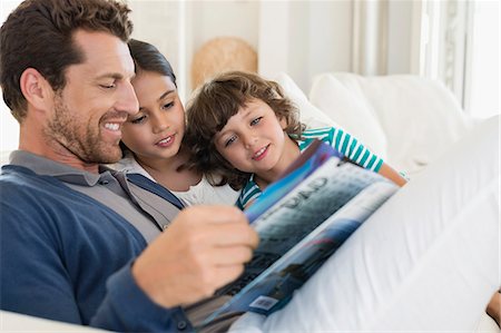 Man reading a magazine with his children Stock Photo - Premium Royalty-Free, Code: 6108-06905554