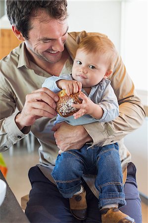 dar de comer - Man feeding bread to his son at a kitchen counter Foto de stock - Sin royalties Premium, Código: 6108-06905560