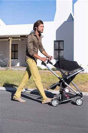 pushing - Man pushing a baby stroller on a road Stock Photo - Premium Royalty-Free, Code: 6108-06905582