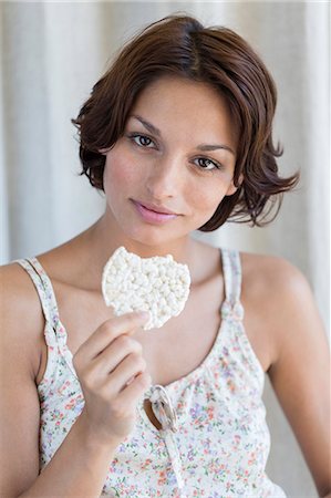 person holding cookie - Portrait of a woman eating rice cake Stock Photo - Premium Royalty-Free, Code: 6108-06905519