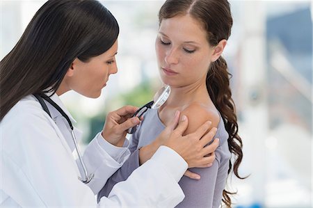 Dermatologist using magnifying glass to examine woman's skin Photographie de stock - Premium Libres de Droits, Code: 6108-06905646