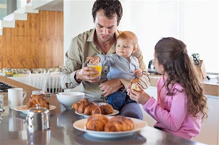 Family having breakfast at a kitchen counter Photographie de stock - Premium Libres de Droits, Code: 6108-06905618