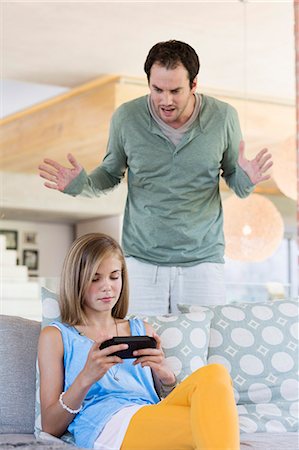 Man scolding his daughter for playing video game Photographie de stock - Premium Libres de Droits, Code: 6108-06905621