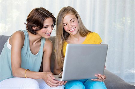 Smiling mother and daughter looking at a laptop Stock Photo - Premium Royalty-Free, Code: 6108-06905630