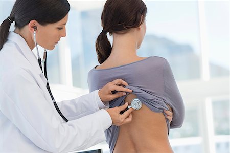 doctor examine patient - Female doctor examining a woman's back with a stethoscope Stock Photo - Premium Royalty-Free, Code: 6108-06905639