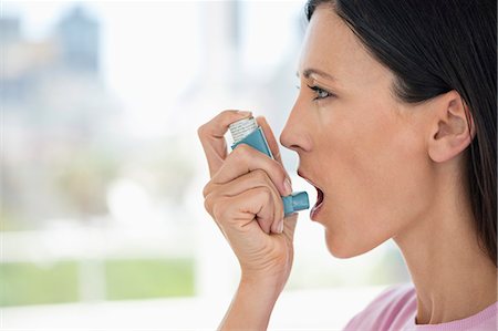 Close-up of a woman using an asthma inhaler Photographie de stock - Premium Libres de Droits, Code: 6108-06905714