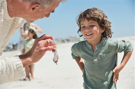 Man showing a jellyfish to his grandson on the beach Photographie de stock - Premium Libres de Droits, Code: 6108-06905899