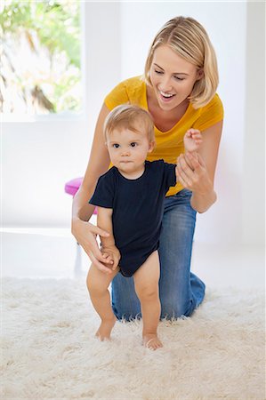 Smiling mother helping her baby to walk Stock Photo - Premium Royalty-Free, Code: 6108-06906044