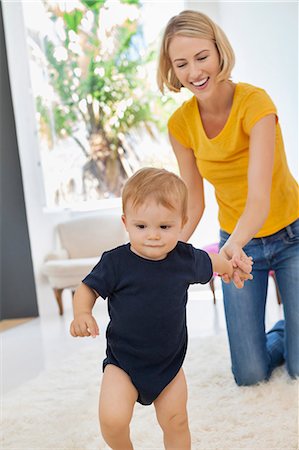 Smiling mother helping her baby to walk Stock Photo - Premium Royalty-Free, Code: 6108-06906098