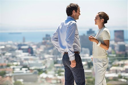 standing talking people lifestyle - Couple discussing on a terrace with city in the background Stock Photo - Premium Royalty-Free, Code: 6108-06906152