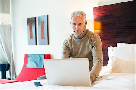 Man using a laptop in a hotel room Stock Photo - Premium Royalty-Free, Code: 6108-06906114