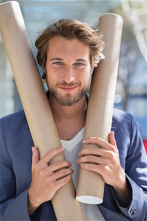 people portraits on work - Portrait of an architect holding paper rolls and smiling Stock Photo - Premium Royalty-Free, Code: 6108-06906119