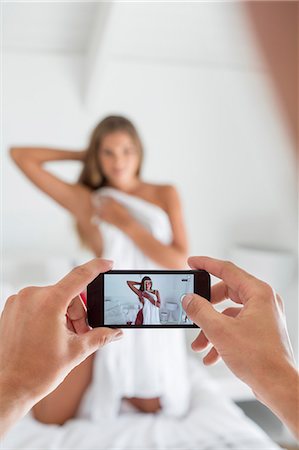 Man taking picture of his girlfriend in the bedroom Stock Photo - Premium Royalty-Free, Code: 6108-06906253