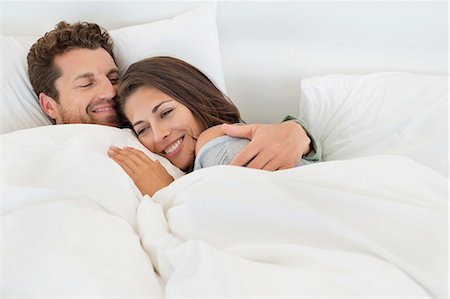 pillow - Smiling couple lying on the bed Stock Photo - Premium Royalty-Free, Code: 6108-06906232
