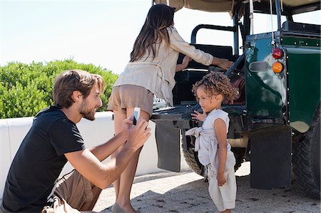 family traveling bag - Man taking a picture of his daughter with a smartphone beside a SUV Stock Photo - Premium Royalty-Free, Code: 6108-06906317
