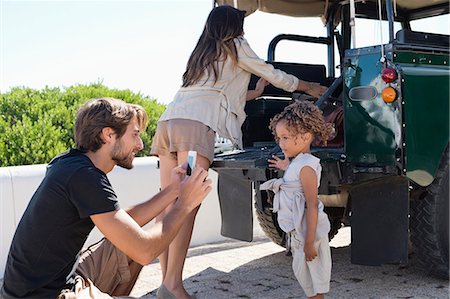 smartphone, car, smiling - Man taking a picture of his daughter with a smartphone beside a SUV Stock Photo - Premium Royalty-Free, Code: 6108-06906317