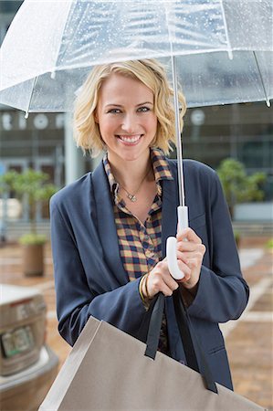 spend money - Portrait of a smiling woman with an umbrella Stock Photo - Premium Royalty-Free, Code: 6108-06906542