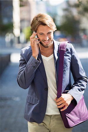 Man walking on a street and talking on a mobile phone Stock Photo - Premium Royalty-Free, Code: 6108-06906545