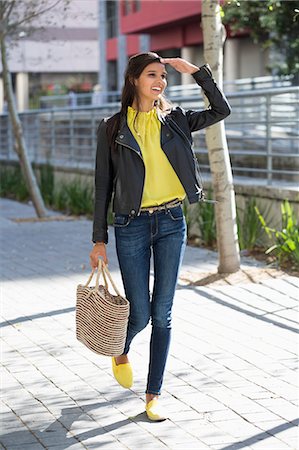 purse - Woman walking on a street and shielding her eyes Stock Photo - Premium Royalty-Free, Code: 6108-06906562