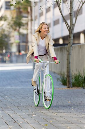 simsearch:6108-06906506,k - Woman riding a bicycle on a street and smiling Foto de stock - Sin royalties Premium, Código: 6108-06906569