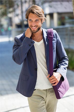 simsearch:6108-06905406,k - Man walking on a street and smiling Stock Photo - Premium Royalty-Free, Code: 6108-06906500