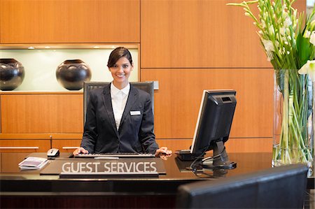Portrait of a receptionist smiling at the hotel reception counter Stock Photo - Premium Royalty-Free, Code: 6108-06906686