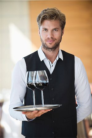 Portrait of a waiter holding a tray of wine glasses in a restaurant Photographie de stock - Premium Libres de Droits, Code: 6108-06906759