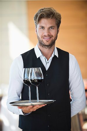 Portrait of a waiter holding a tray of wine glasses in a restaurant Photographie de stock - Premium Libres de Droits, Code: 6108-06906762