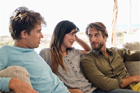 Three friends sitting together on a couch Stock Photo - Premium Royalty-Free, Code: 6108-06906782