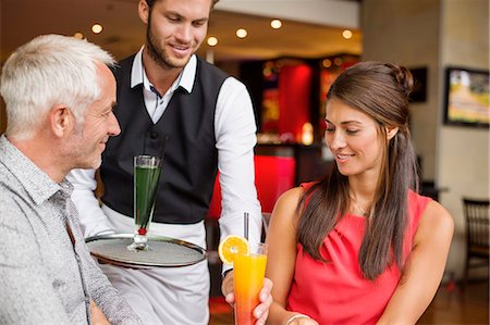 sitting at bar - Waiter serving drinks to a couple in a restaurant Photographie de stock - Premium Libres de Droits, Code: 6108-06906702