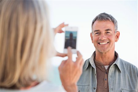 simsearch:6108-06906865,k - Woman taking a picture of her husband with a cell phone on the beach Stock Photo - Premium Royalty-Free, Code: 6108-06906856