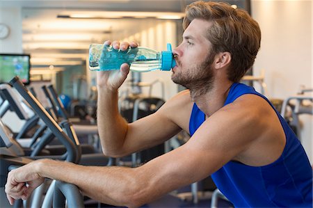 drinking water bottle - Man drinking water from a bottle at a gym Stock Photo - Premium Royalty-Free, Code: 6108-06907001