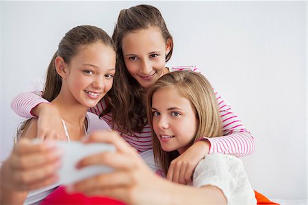 simsearch:6108-06907667,k - Three girls taking a picture of themselves with a mobile phone at a slumber party Stock Photo - Premium Royalty-Free, Code: 6108-06907026