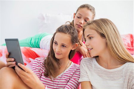 Three girls using a digital tablet at a slumber party Photographie de stock - Premium Libres de Droits, Code: 6108-06907033