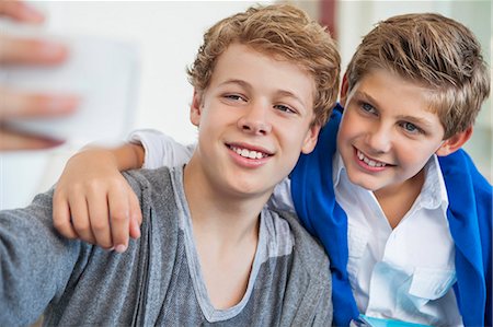 Two teenage boys taking a picture of themselves with a mobile phone Foto de stock - Sin royalties Premium, Código: 6108-06907036