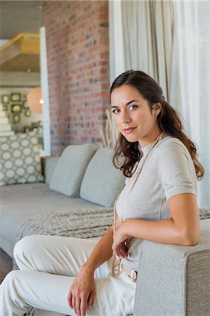 Portrait of a beautiful woman sitting on a couch Stock Photo - Premium Royalty-Free, Code: 6108-06907154