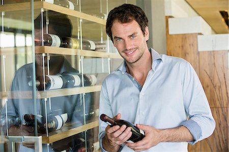 Portrait of a smiling man holding a wine bottle Foto de stock - Sin royalties Premium, Código: 6108-06907123