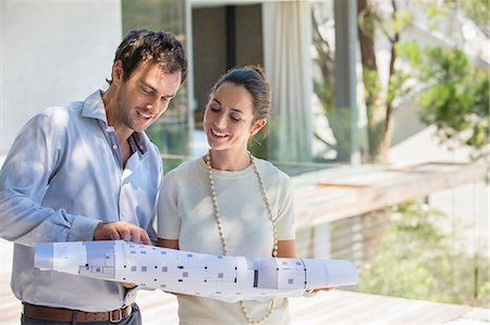 renovate house - Couple looking at blueprint and smiling Stock Photo - Premium Royalty-Free, Code: 6108-06907127
