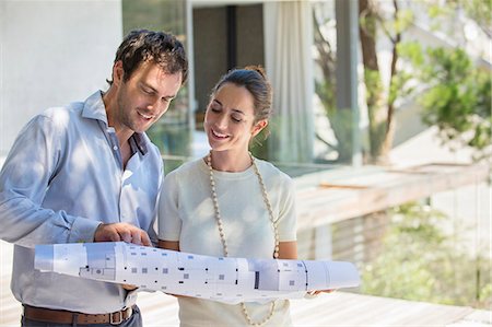 Couple looking at blueprint and smiling Photographie de stock - Premium Libres de Droits, Code: 6108-06907127