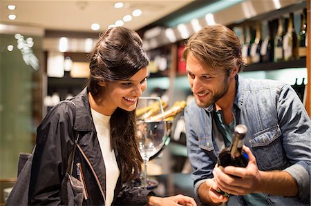 Sales clerk showing a wine bottle to a customer Foto de stock - Sin royalties Premium, Código: 6108-06907132