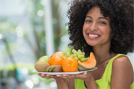 simsearch:6108-06907432,k - Smiling woman holding a plate of fruits Stockbilder - Premium RF Lizenzfrei, Bildnummer: 6108-06907366