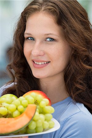 Smiling woman holding a plate of fruits Stock Photo - Premium Royalty-Free, Code: 6108-06907443