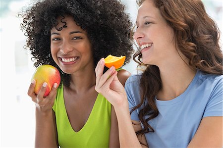 Close-up of two female friends eating fruits Photographie de stock - Premium Libres de Droits, Code: 6108-06907448