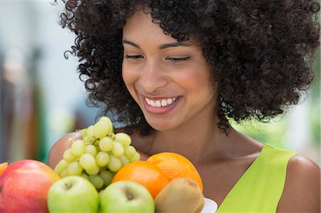 Smiling woman holding a plate of fruits Photographie de stock - Premium Libres de Droits, Code: 6108-06907413