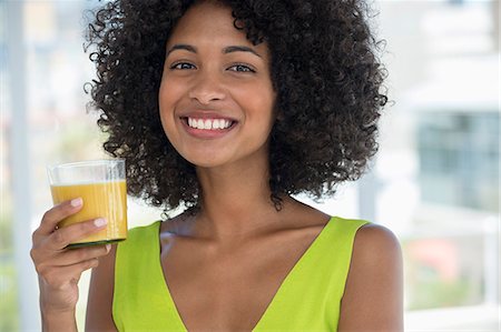 Portrait of a smiling woman holding a glass of mango shake Stock Photo - Premium Royalty-Free, Code: 6108-06907417