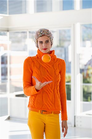 Portrait of a woman tossing an orange Stock Photo - Premium Royalty-Free, Code: 6108-06907414